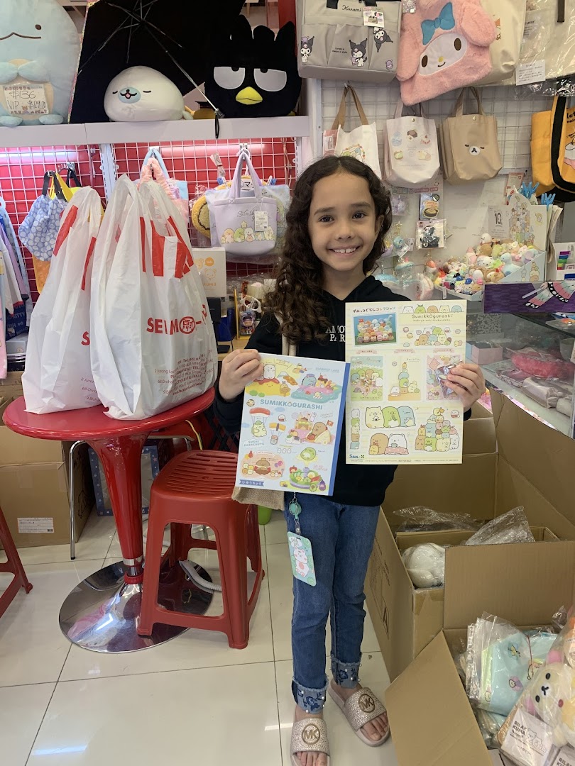 A young girl smiles while holding Sumikko Gurashi merchandise inside a vibrant retail store.
