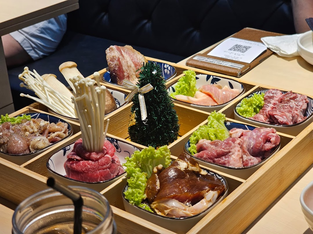 A wooden tray filled with various raw meats, mushrooms, and lettuce, ready for Korean BBQ.