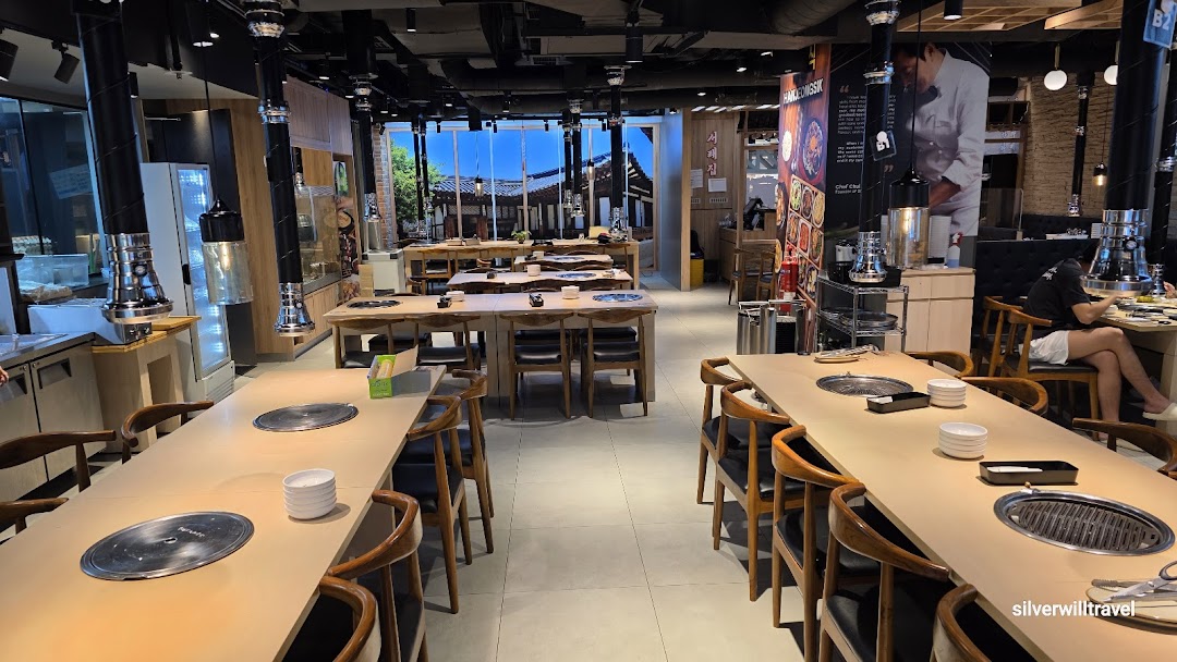Spacious interior of a Korean BBQ restaurant featuring multiple tables with built-in grills and traditional decor.