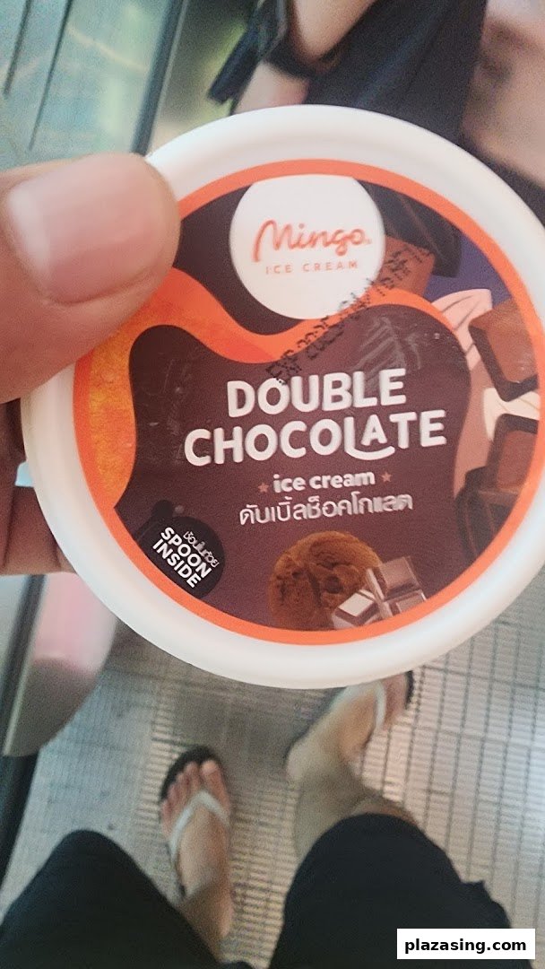 A hand holds a Mingo Double Chocolate ice cream cup, featuring its label and 'spoon inside' detail.