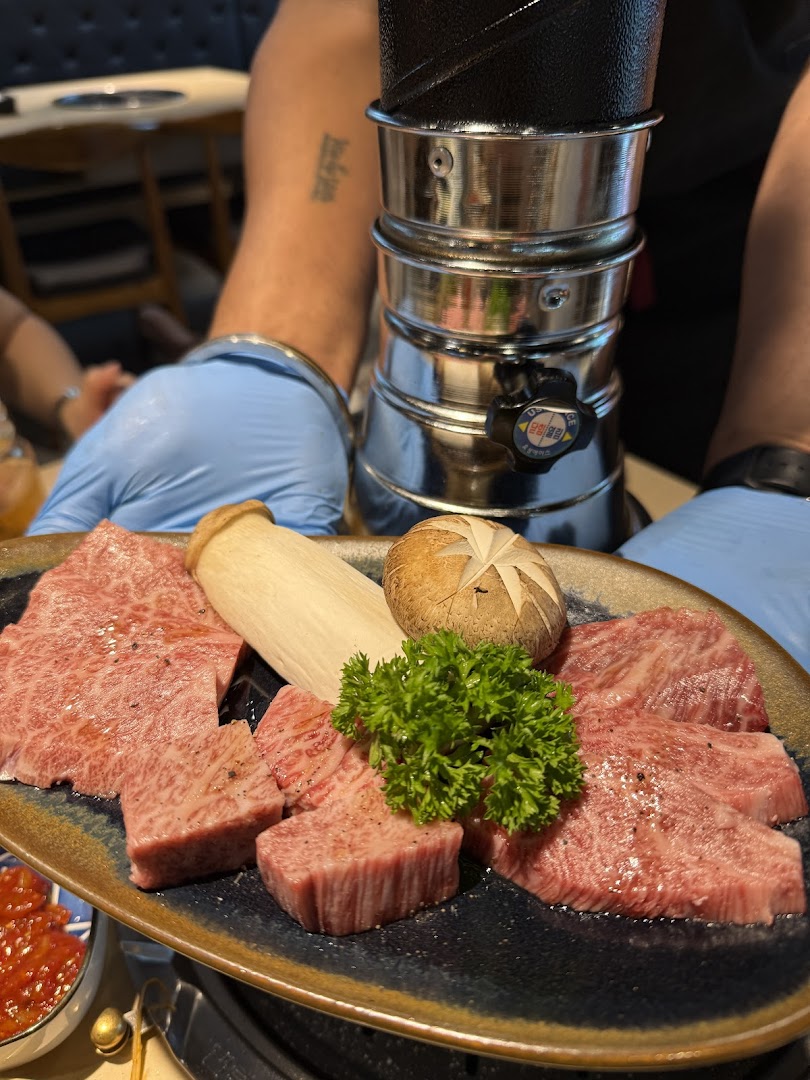 A plate of premium raw beef cuts with mushrooms and parsley, ready for grilling.