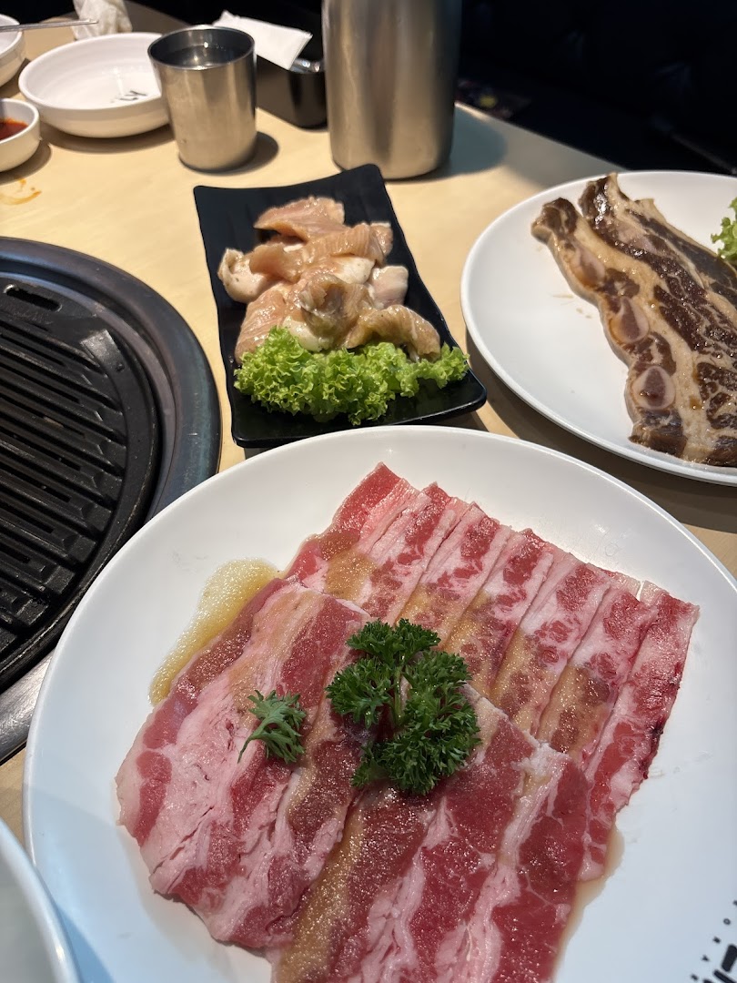 Plates of fresh raw meat cuts, including beef and ribs, ready for grilling at a Korean BBQ.