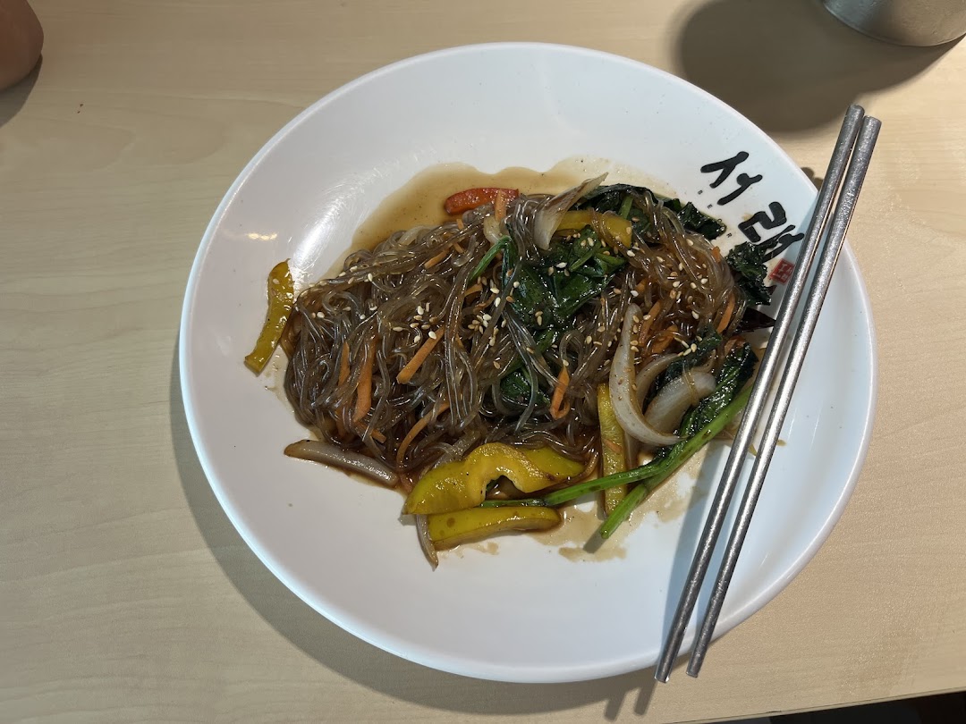 A delicious plate of Korean glass noodles (Japchae) with vegetables and chopsticks.