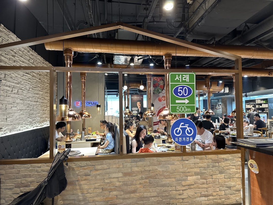 Diners enjoy a meal inside Seorae Jib Korean BBQ restaurant, featuring distinctive copper exhaust hoods.