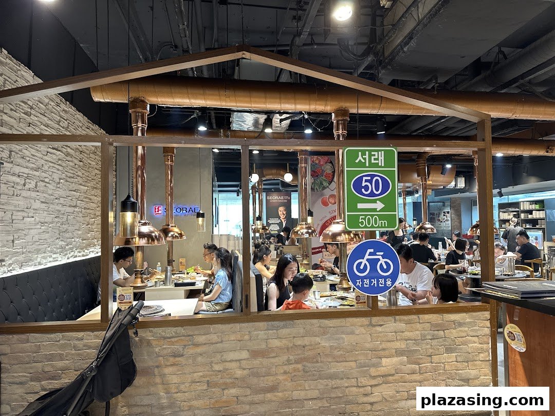 Diners enjoy a meal inside Seorae Jib Korean BBQ restaurant, featuring distinctive copper exhaust hoods.