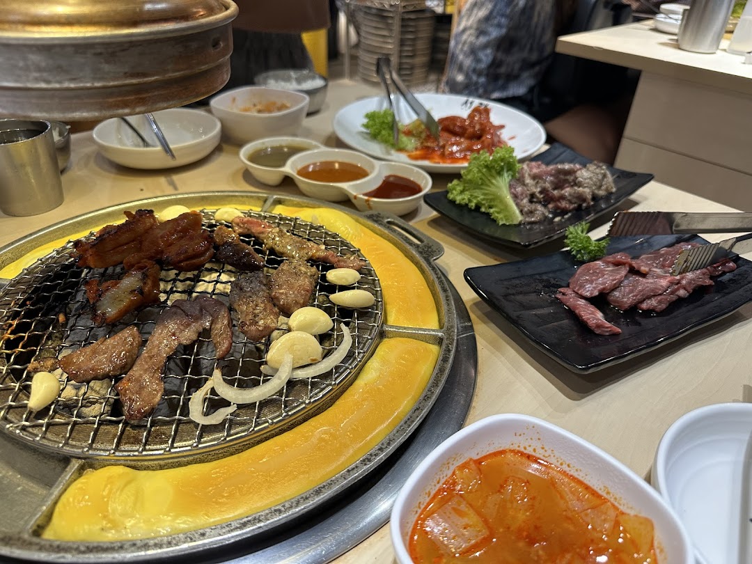 Delicious Korean BBQ grilling on a tabletop, surrounded by various side dishes and fresh meats.