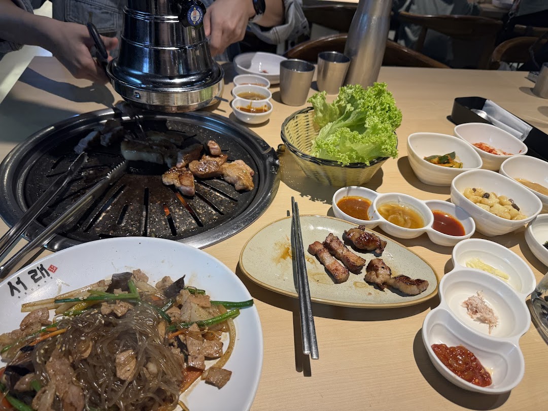 A table laden with Korean BBQ, banchan, and japchae, ready for a delicious meal.