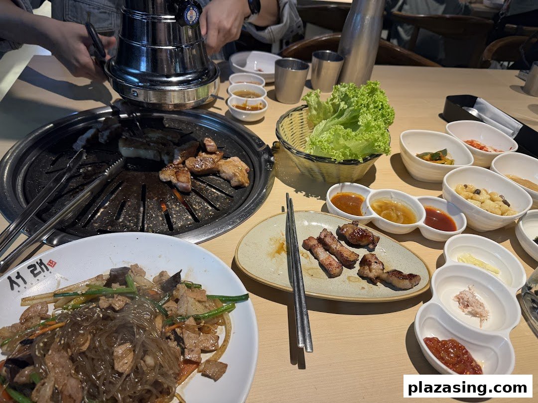 A table laden with Korean BBQ, banchan, and japchae, ready for a delicious meal.