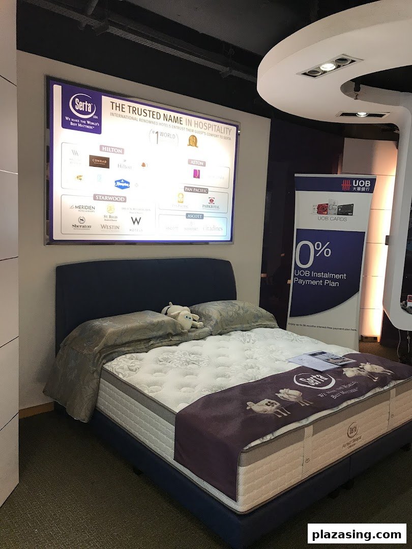 A Serta mattress display featuring a bed, promotional banner, and a list of hospitality partners.
