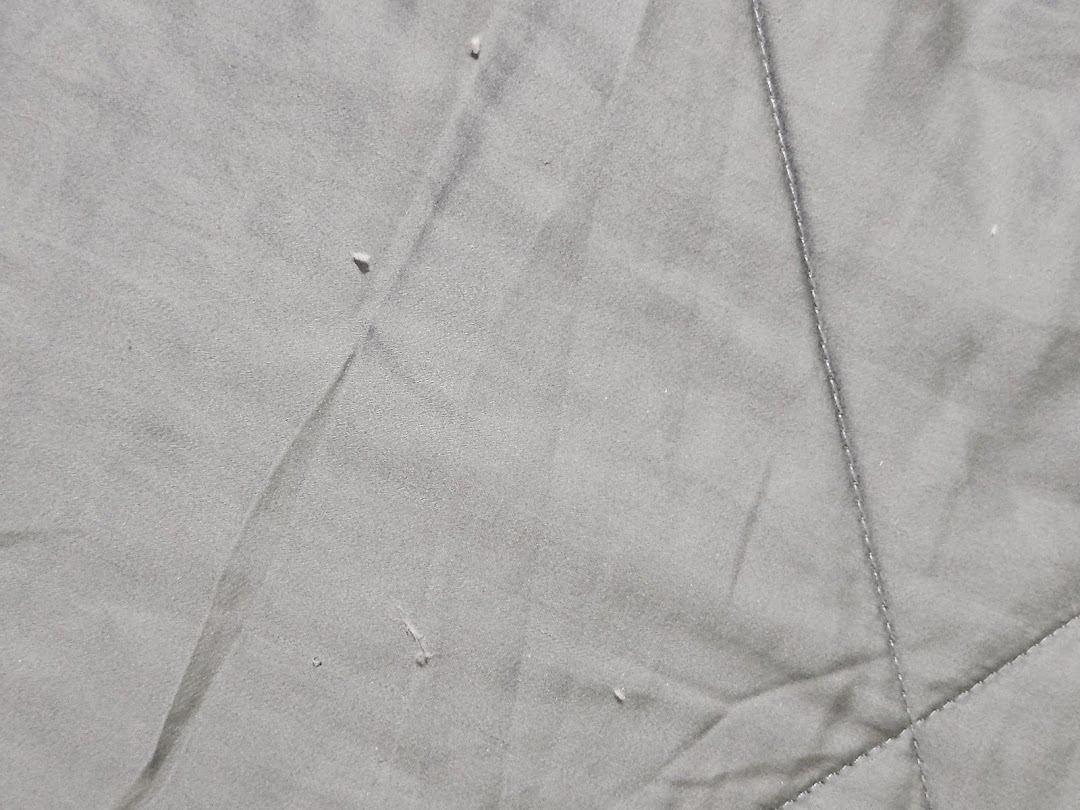 Close-up of grey, textured fabric with stitching, likely from a Serta mattress or bedding.