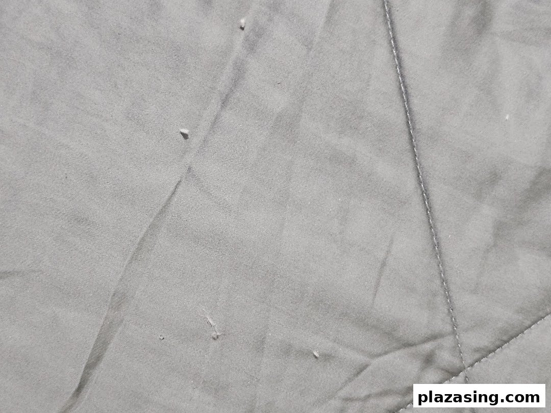 Close-up of grey, textured fabric with stitching, likely from a Serta mattress or bedding.