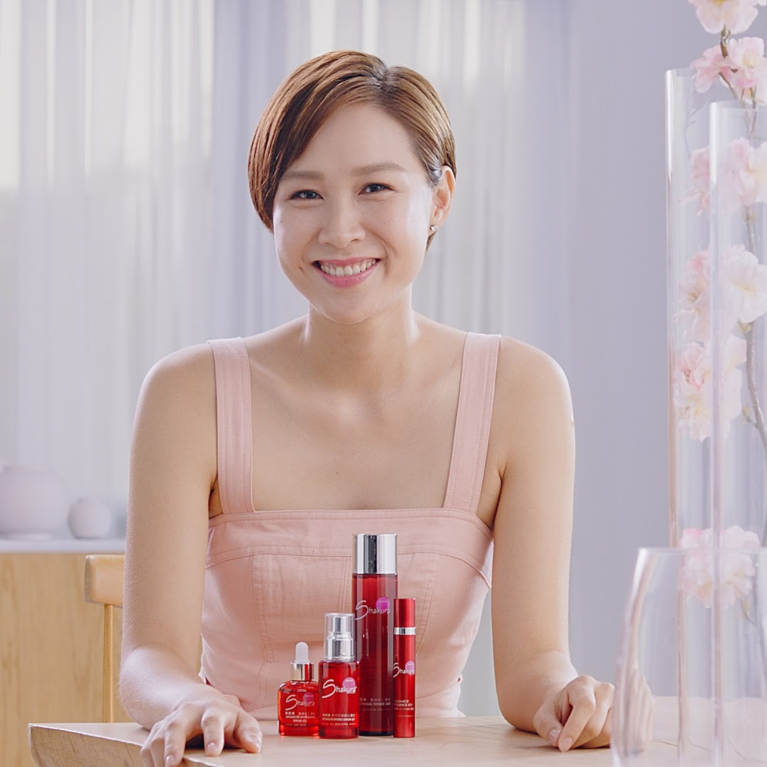 A smiling woman poses with Shakura pigmentation beauty products on a wooden table.