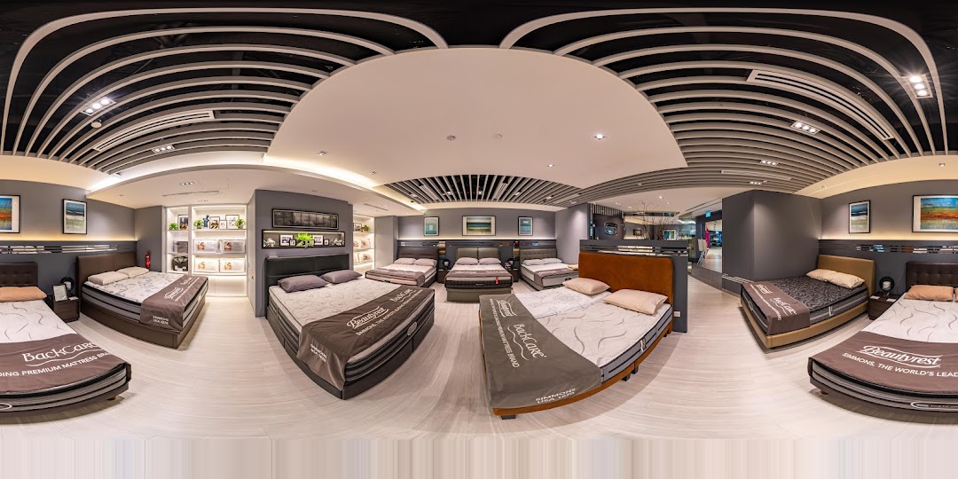 A wide-angle view of the Simmons Studio showroom, showcasing various mattresses and bed frames in a modern setting.