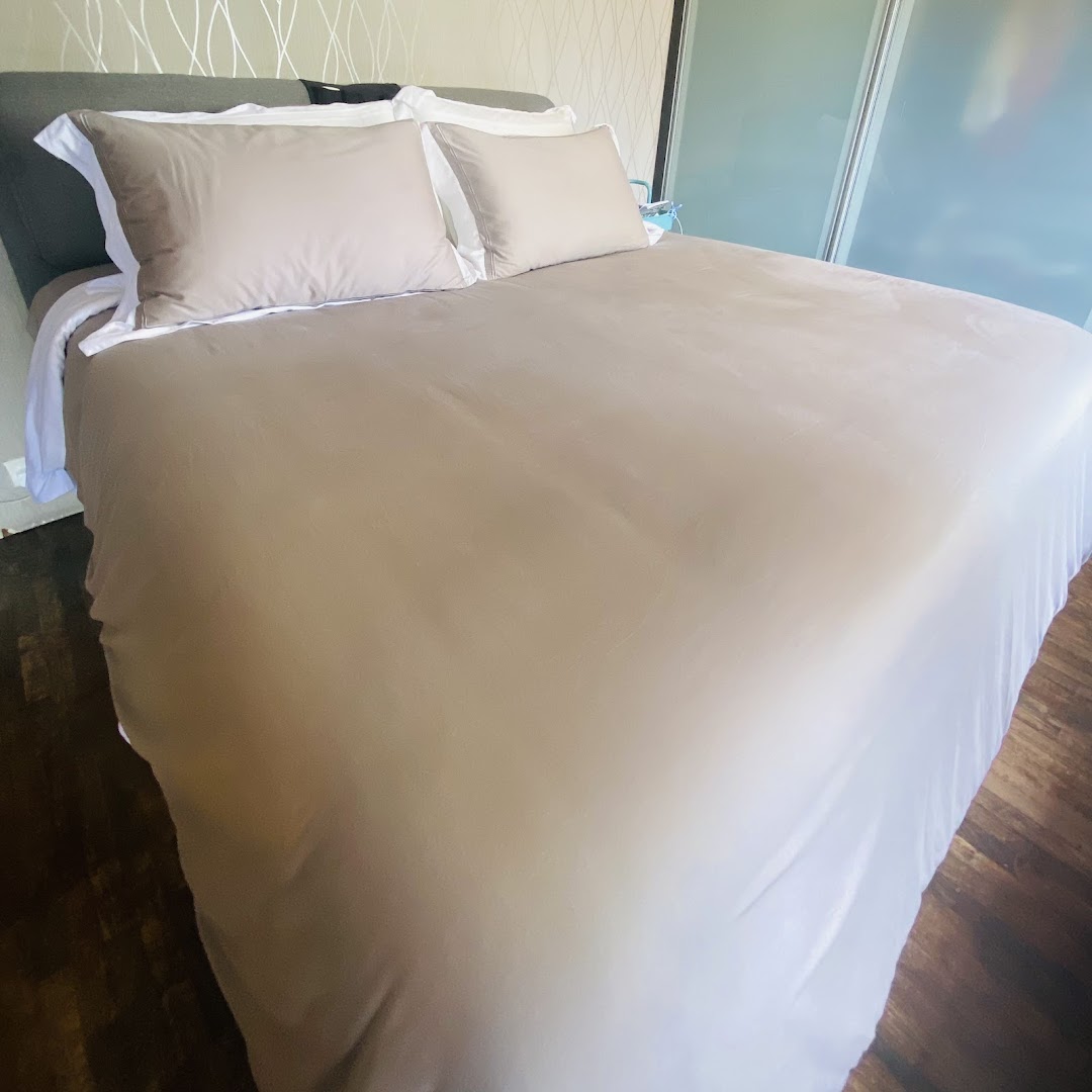 A neatly made bed featuring a neutral-toned duvet and pillows, showcasing comfortable bedding.