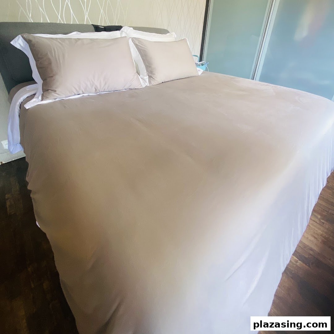 A neatly made bed featuring a neutral-toned duvet and pillows, showcasing comfortable bedding.
