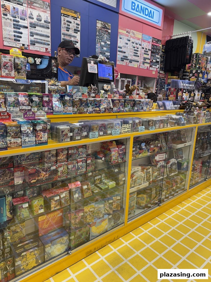 Interior view of Simply Toys, showcasing display cases filled with trading cards and collectibles, with a staff member at the counter.