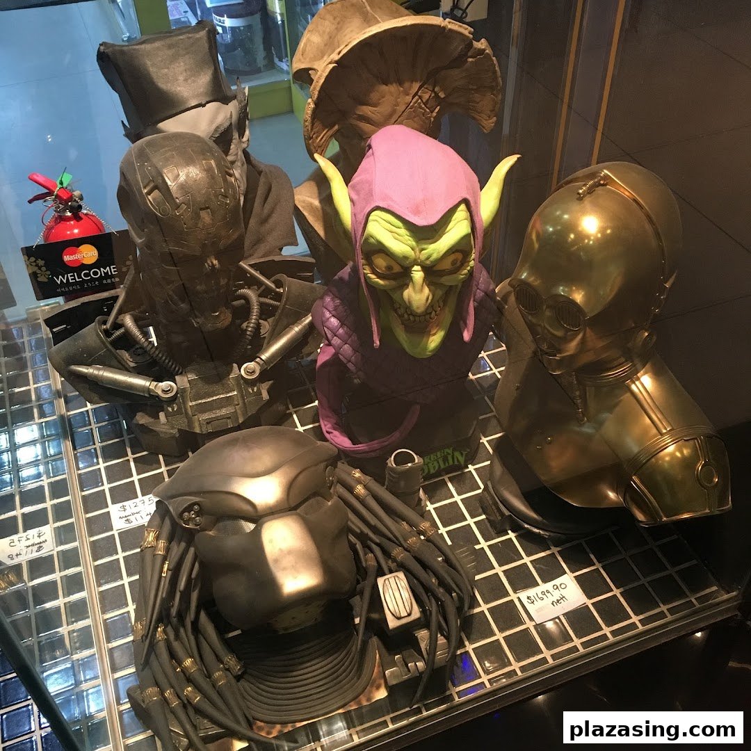 A display of detailed character busts including Green Goblin, C-3PO, and Predator in a retail shop.