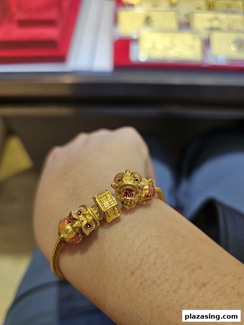 A person's arm showcasing a detailed gold bracelet with intricate charms, likely from a jewellery display.