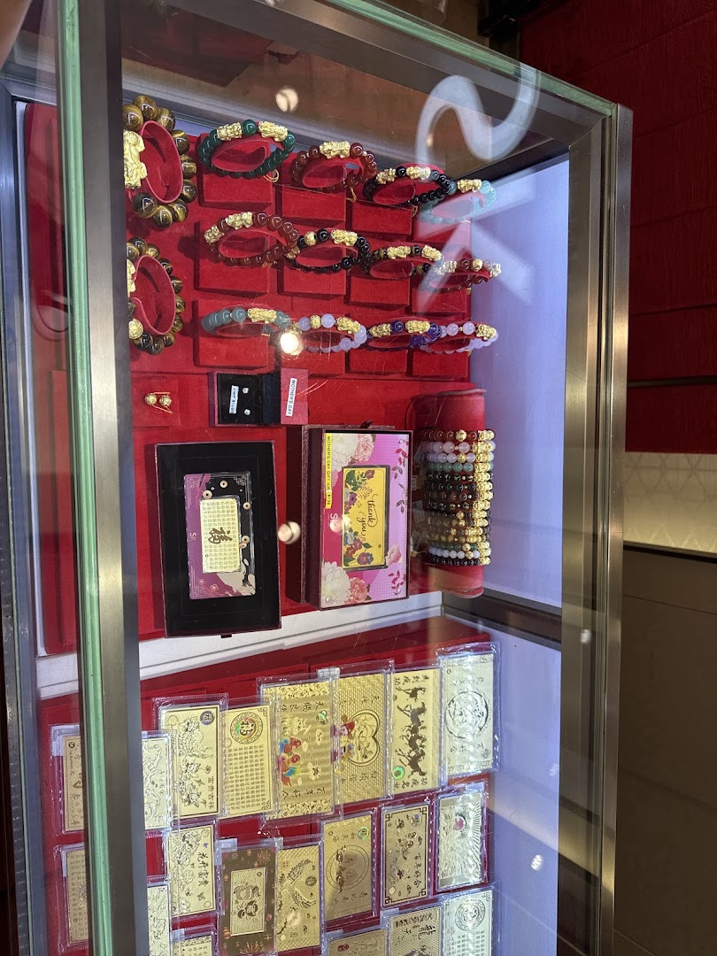 A glass display case showcasing an array of traditional and modern jewellery, including bracelets and gold-plated items.