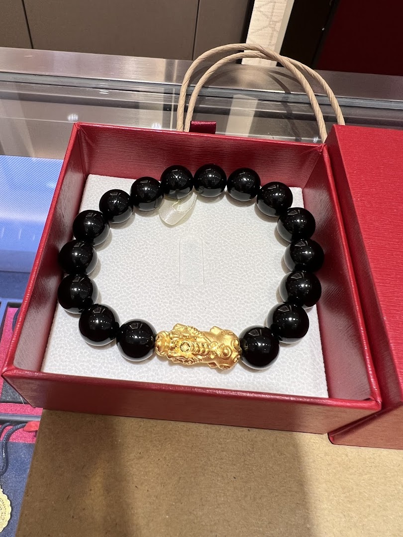 A black beaded bracelet featuring a prominent gold Pixiu charm, presented in a red gift box.