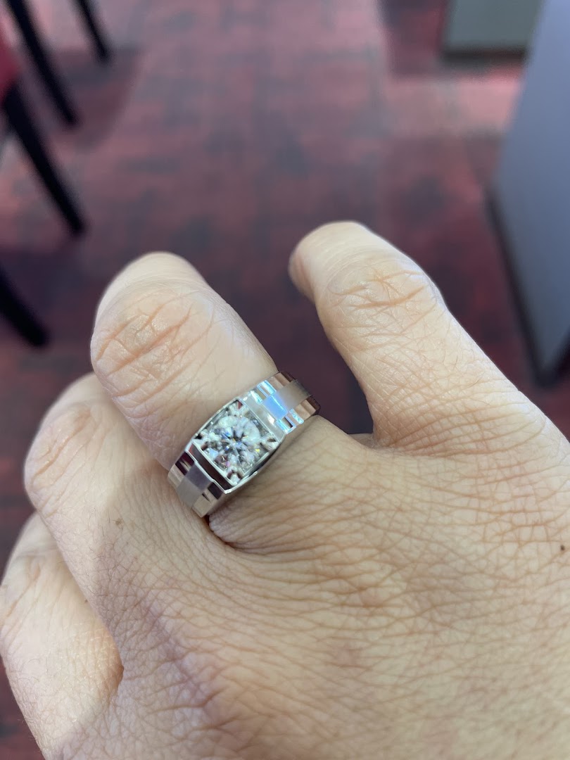 A hand showcasing a modern white gold ring with a brilliant round diamond.
