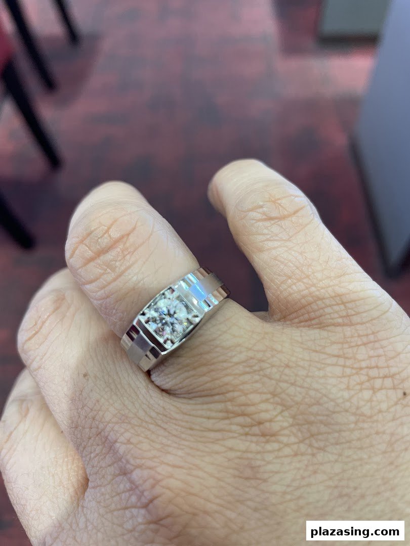 A hand showcasing a modern white gold ring with a brilliant round diamond.