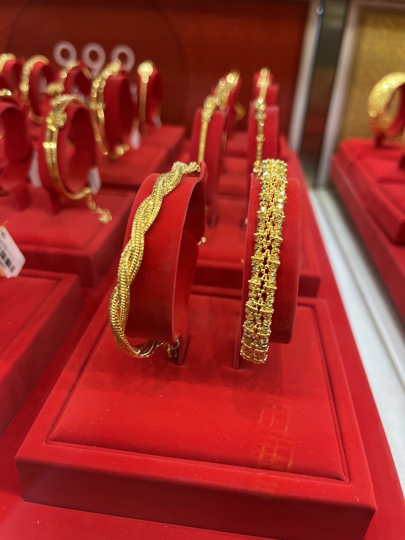 Close-up of intricate gold bracelets displayed on red velvet stands at SK Jewellery.
