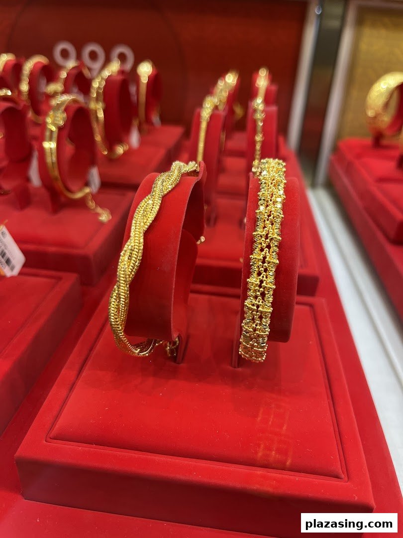 Close-up of intricate gold bracelets displayed on red velvet stands at SK Jewellery.