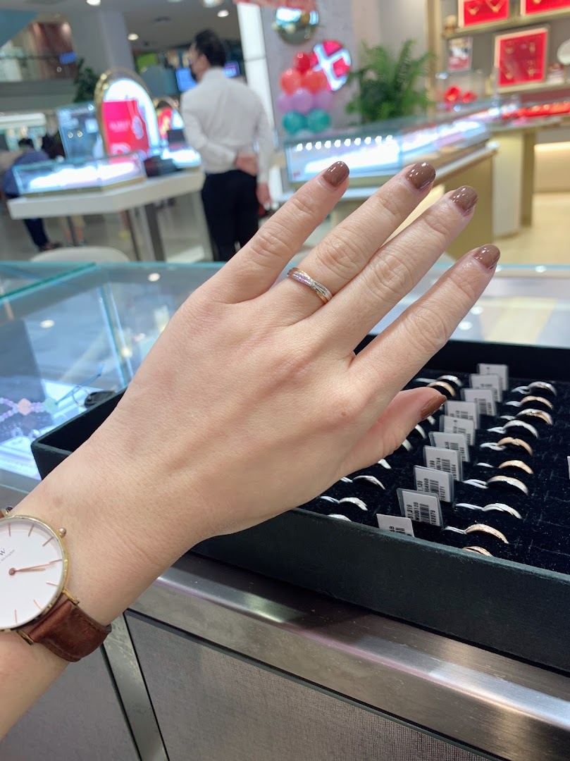A customer's hand trying on a ring, with a display of rings in a jewellery shop.