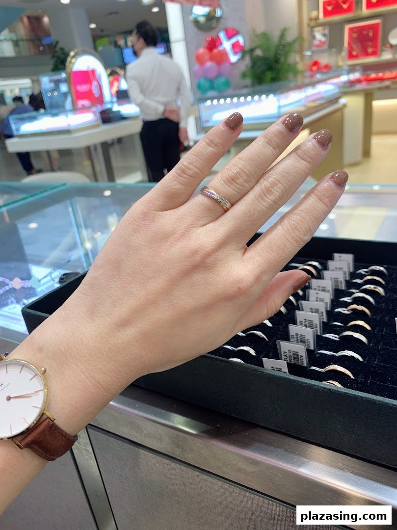 A customer's hand trying on a ring, with a display of rings in a jewellery shop.