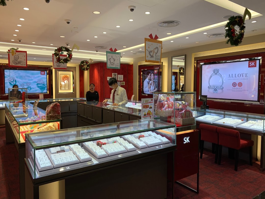 An interior view of SK Jewellery, showcasing sparkling display cases, digital screens, and attentive staff.