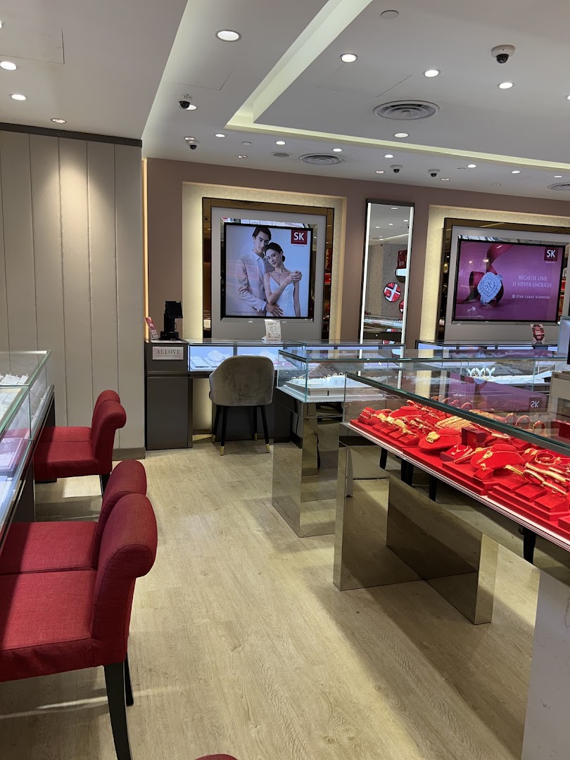 Interior view of SK Jewellery showcasing display cases with gold items, seating, and promotional screens.