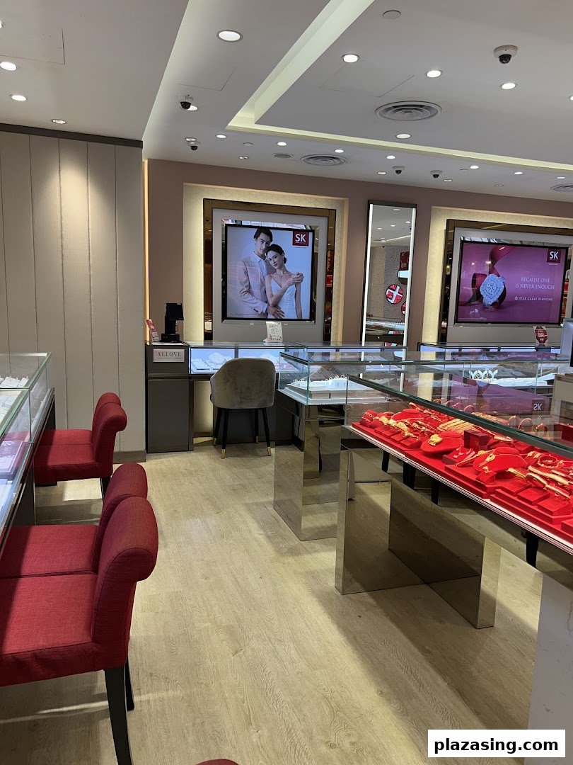 Interior view of SK Jewellery showcasing display cases with gold items, seating, and promotional screens.