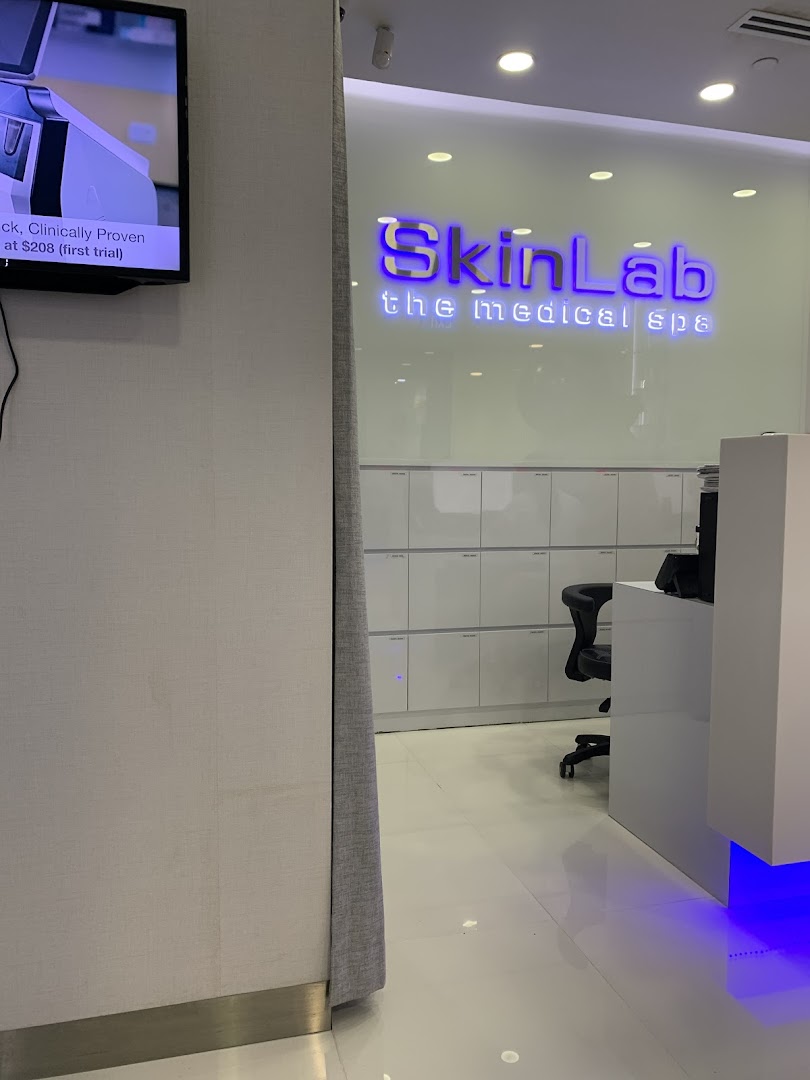 Interior view of SkinLab The Medical Spa reception area, featuring its illuminated logo and a screen displaying an offer.