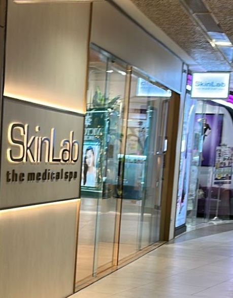The illuminated facade and glass entrance of SkinLab The Medical Spa at Plaza Singapura.