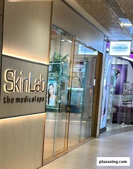 The illuminated facade and glass entrance of SkinLab The Medical Spa at Plaza Singapura.