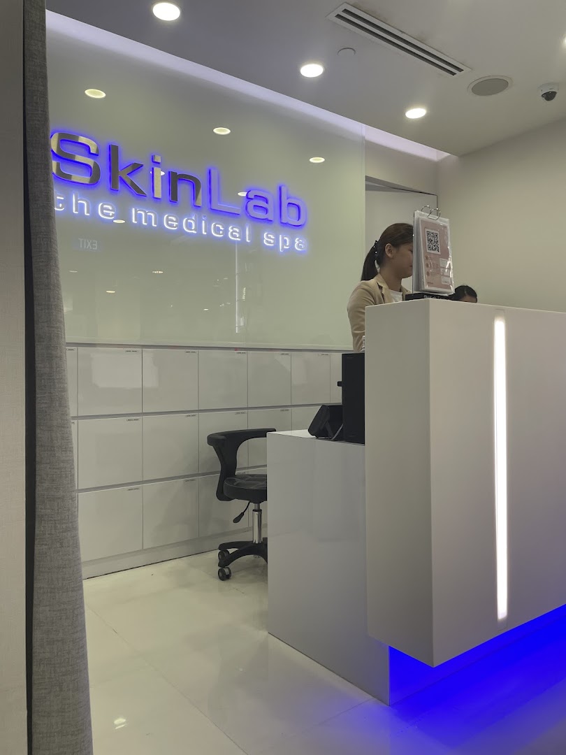 The reception area of SkinLab The Medical Spa, featuring a modern desk, staff member, and illuminated brand signage.