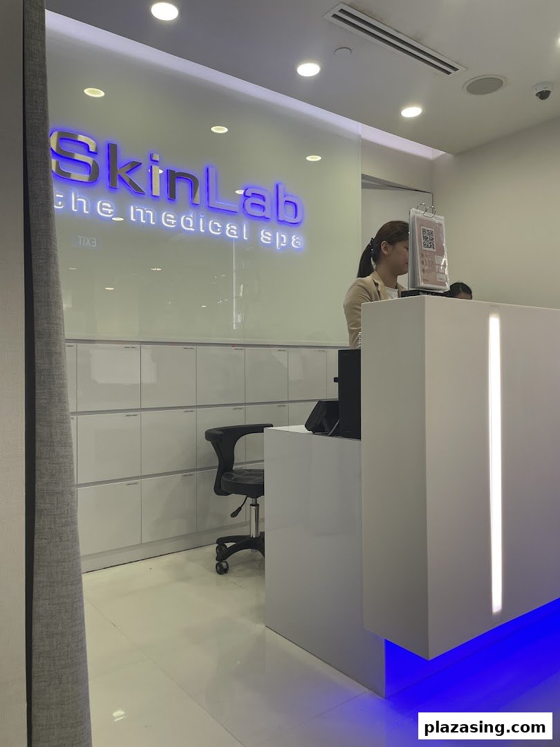The reception area of SkinLab The Medical Spa, featuring a modern desk, staff member, and illuminated brand signage.