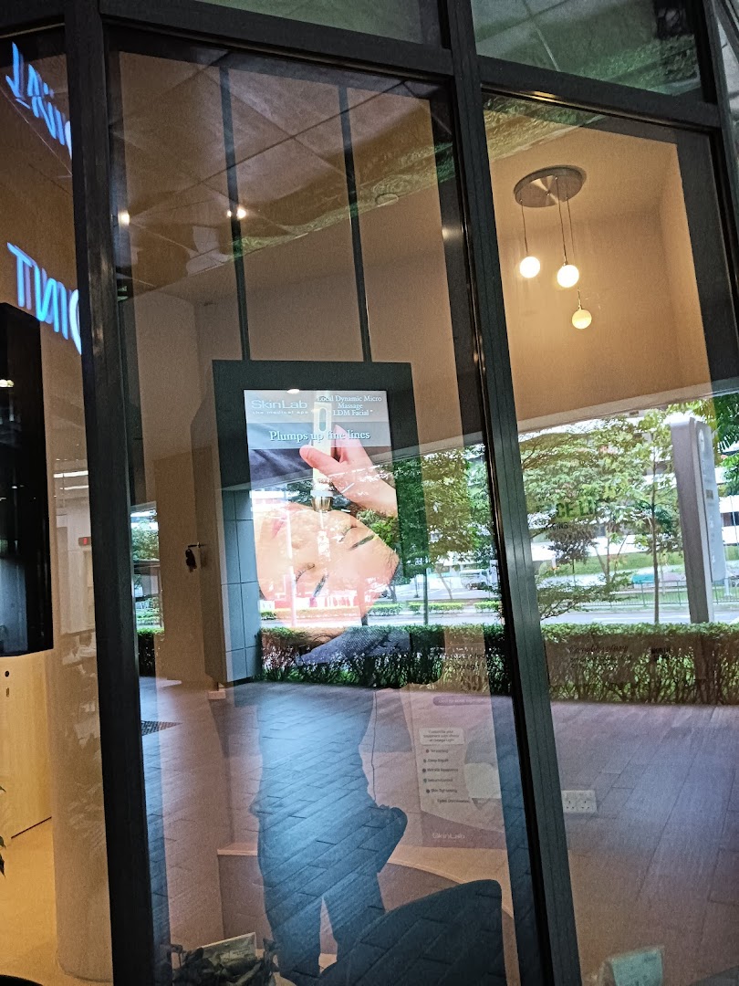 View of SL Aesthetic Clinic's exterior through a glass window, showcasing an internal display and reflections.