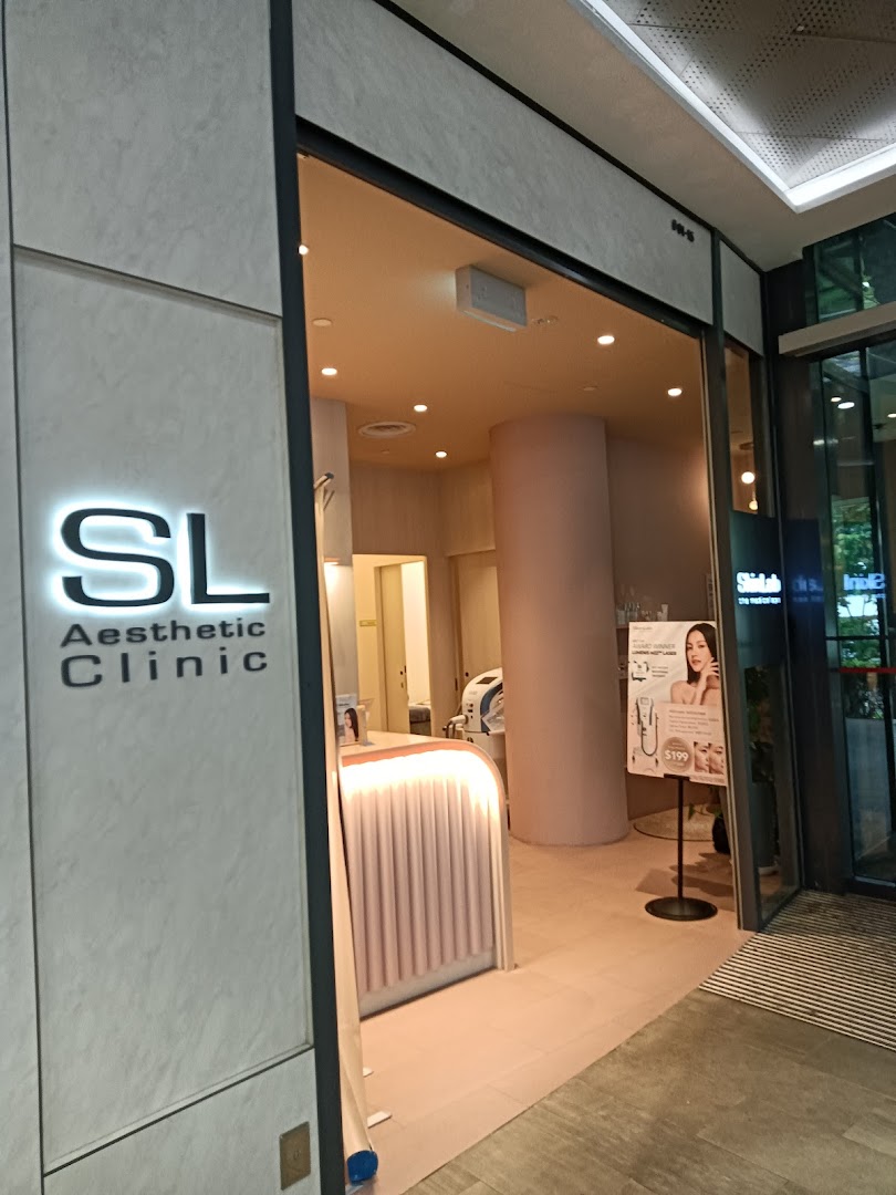 The inviting entrance of SL Aesthetic Clinic with its illuminated logo and a promotional stand.