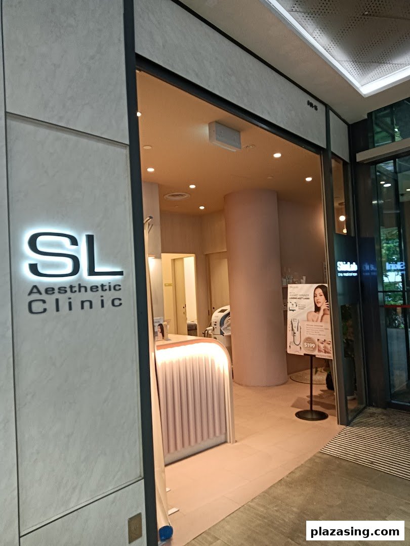 The inviting entrance of SL Aesthetic Clinic with its illuminated logo and a promotional stand.