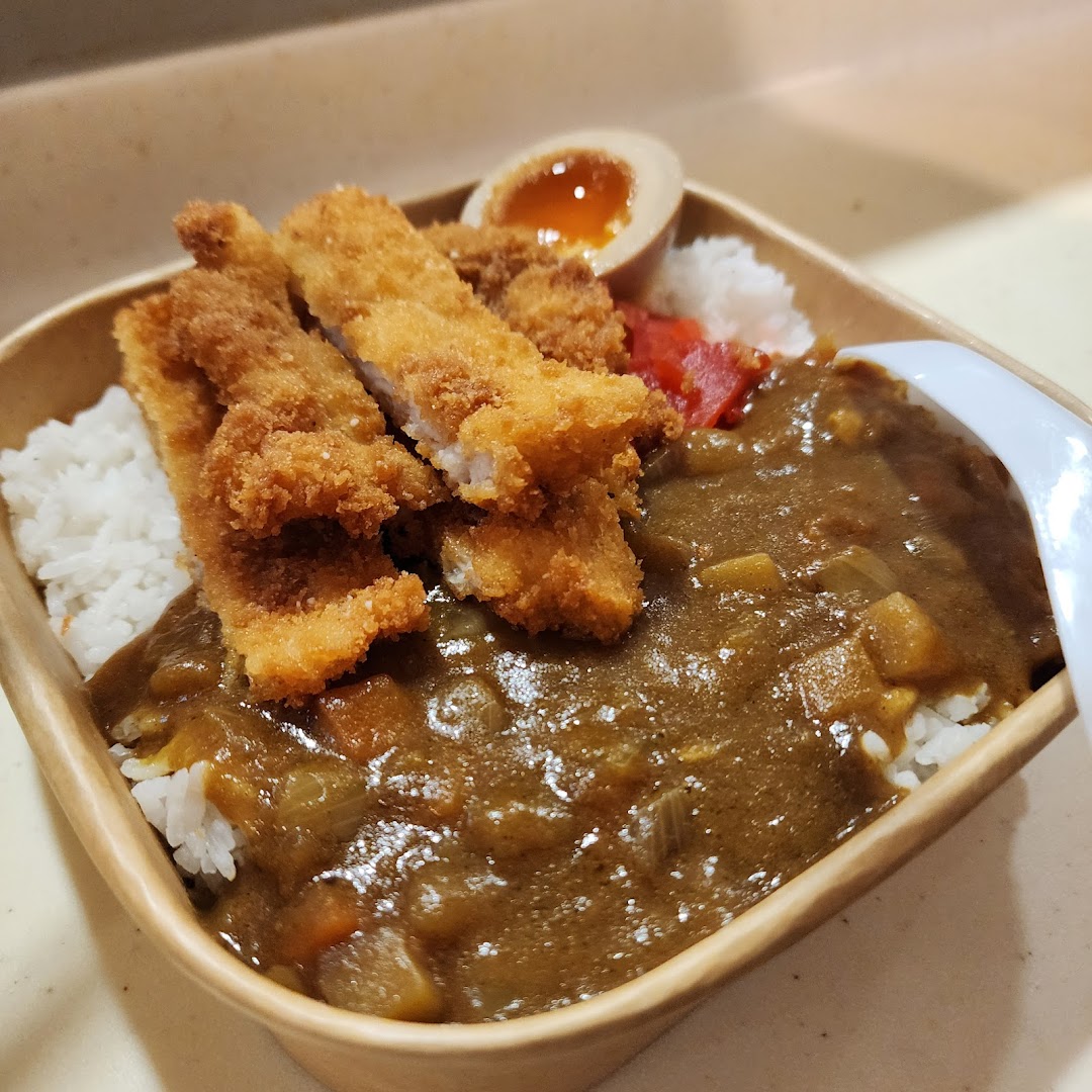 A delicious katsu curry rice bowl with crispy fried cutlets, a soft-boiled egg, and pickled ginger.