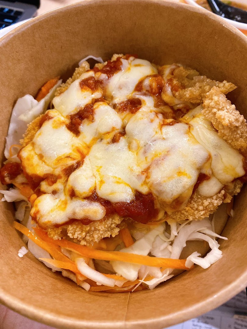 A close-up of a delicious snack bowl featuring crispy fried chicken, melted cheese, rich sauce, and fresh vegetables.