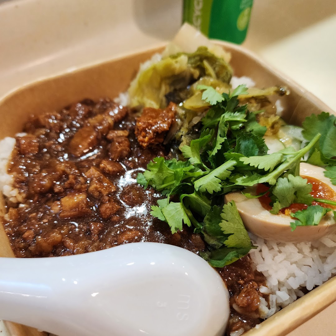 A close-up of a delicious braised pork rice bowl with an egg, greens, and cilantro.