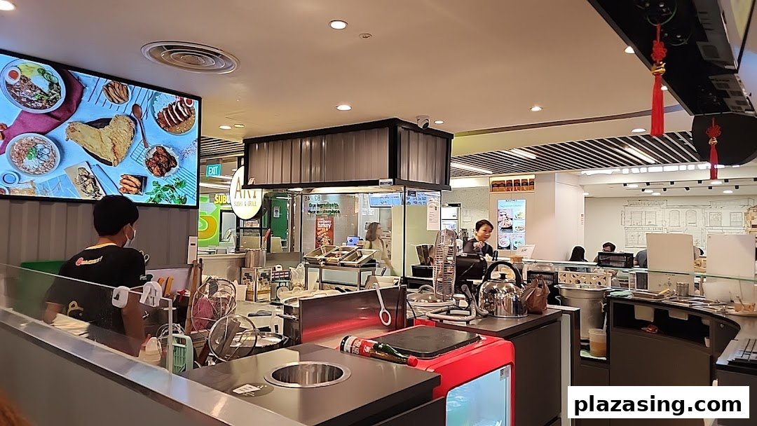 An interior view of Snackz it! food stall, featuring a service counter, staff, and a digital display showcasing food items.