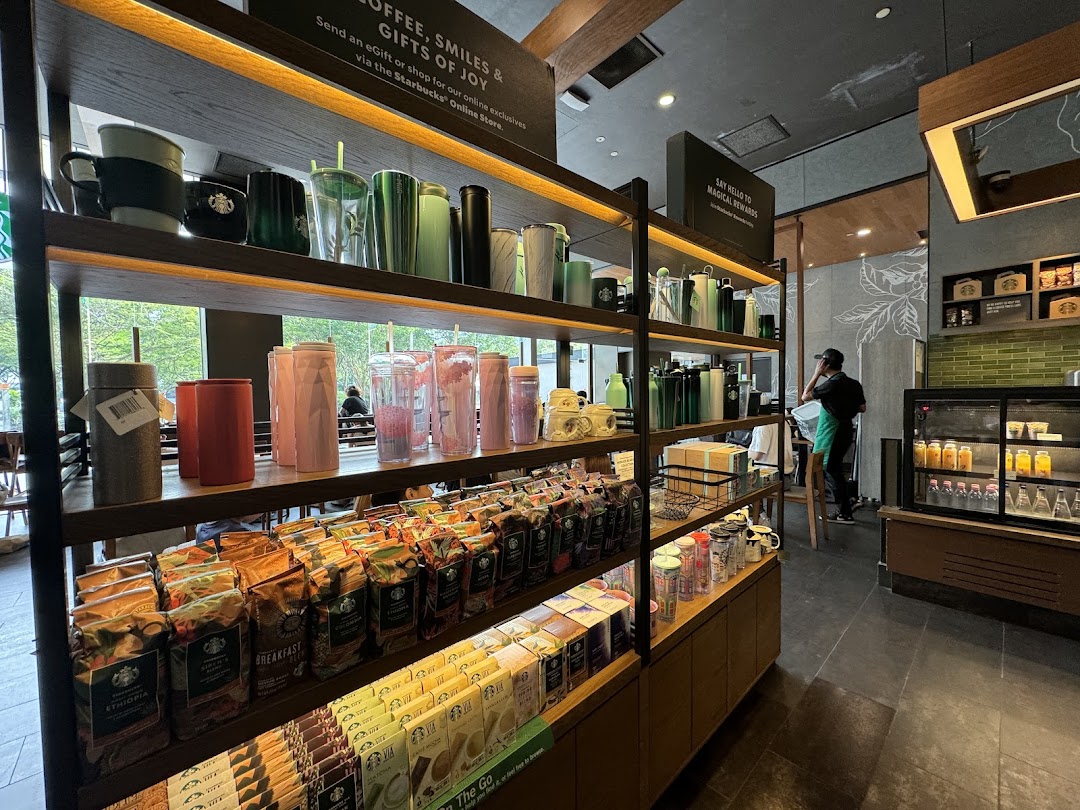 Interior view of Starbucks showcasing merchandise shelves with coffee beans, tumblers, and mugs.