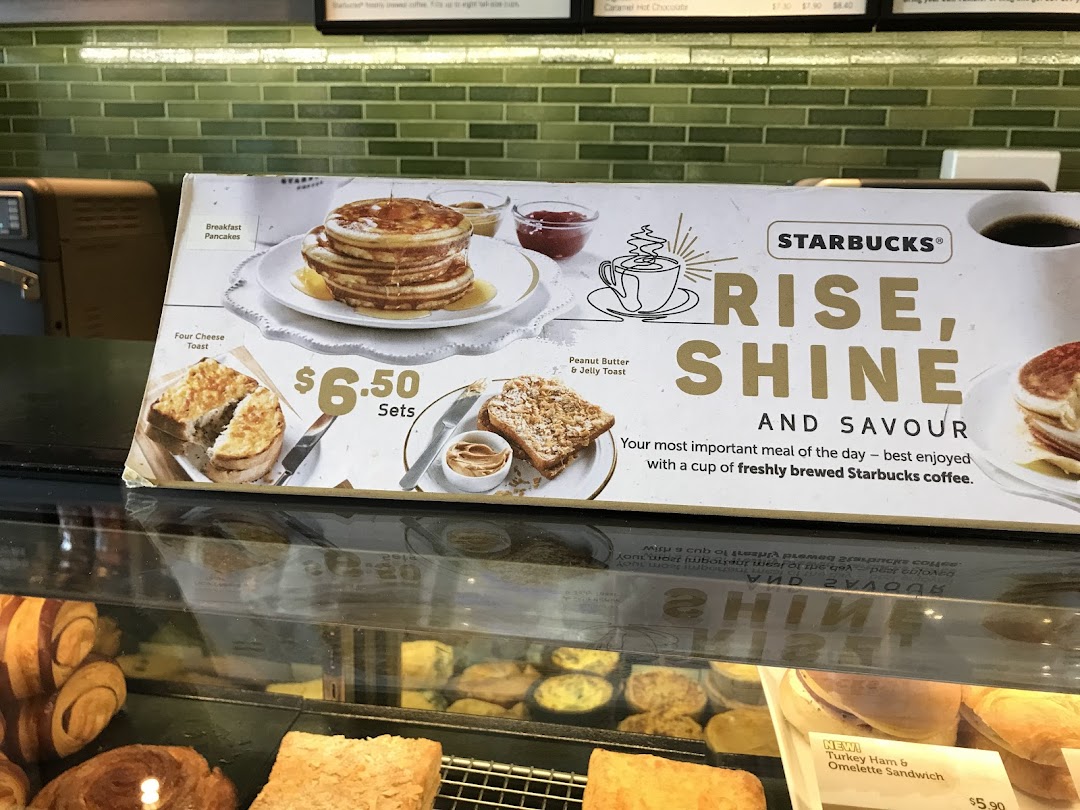 A Starbucks display board showcasing breakfast items and their prices, with a promotional message.