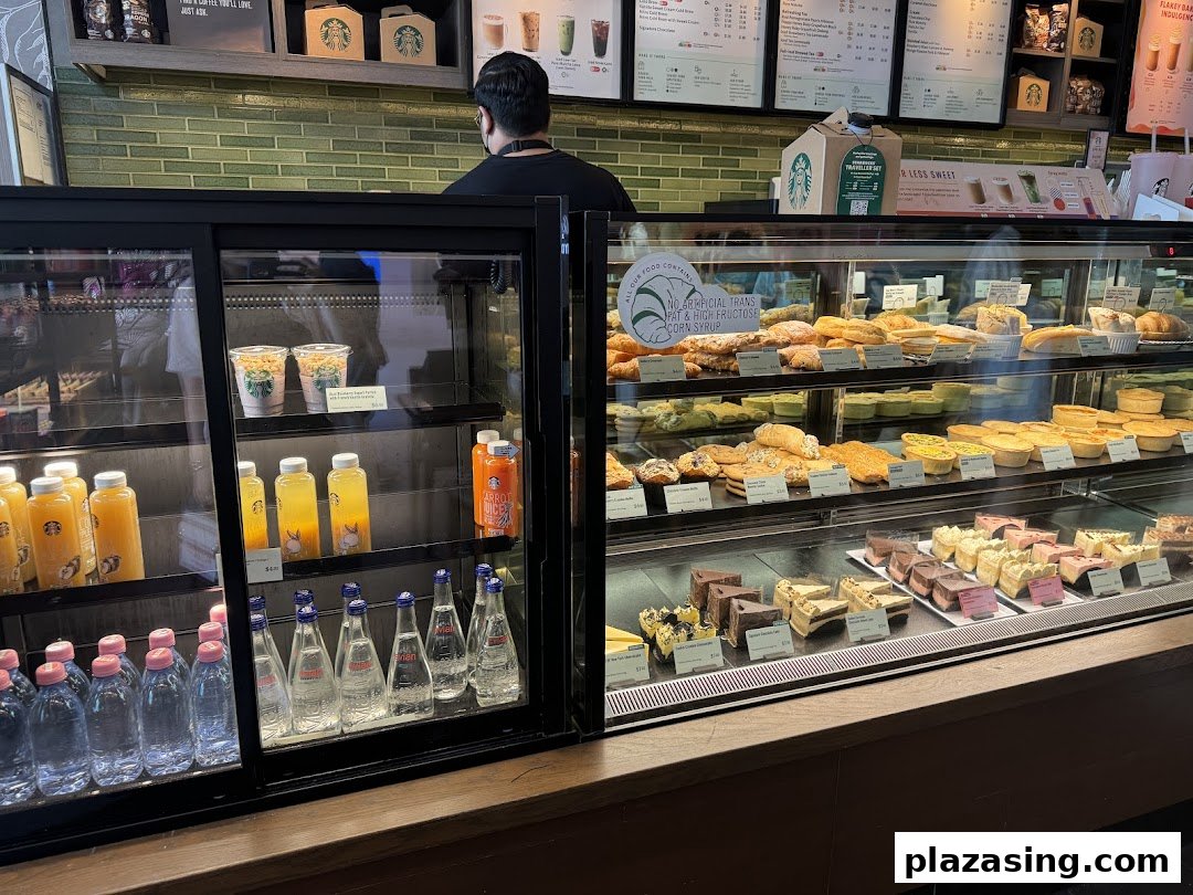Interior view of Starbucks showcasing display cases filled with pastries, cakes, and bottled beverages.