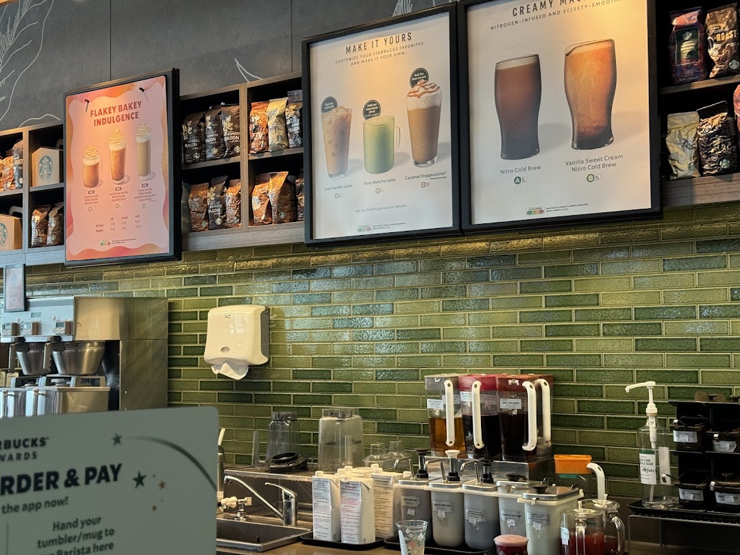An interior view of Starbucks, showcasing the counter, menu boards, and coffee preparation area.