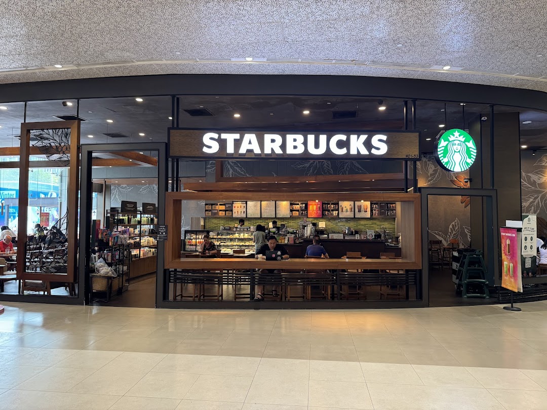 The inviting exterior of Starbucks Plaza Singapura, showcasing its entrance and interior seating area.